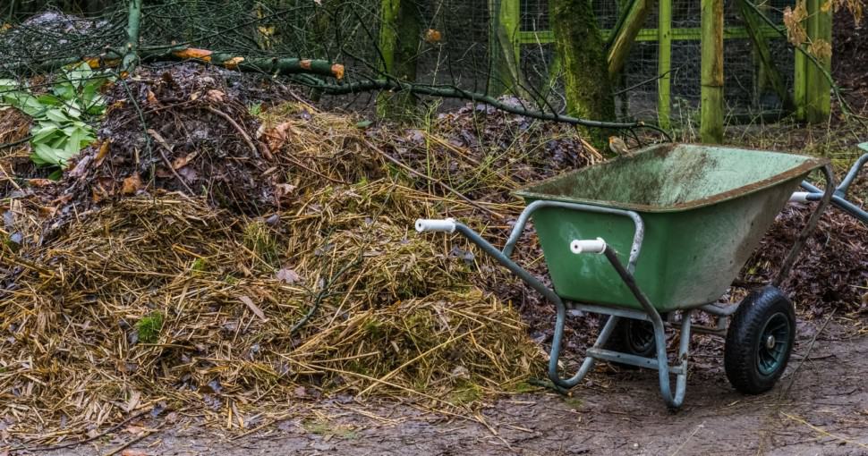 wheelbarrow next to a compost pile