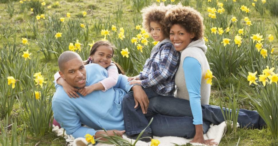 Family Relaxing In Field Of Spring Daffodils
